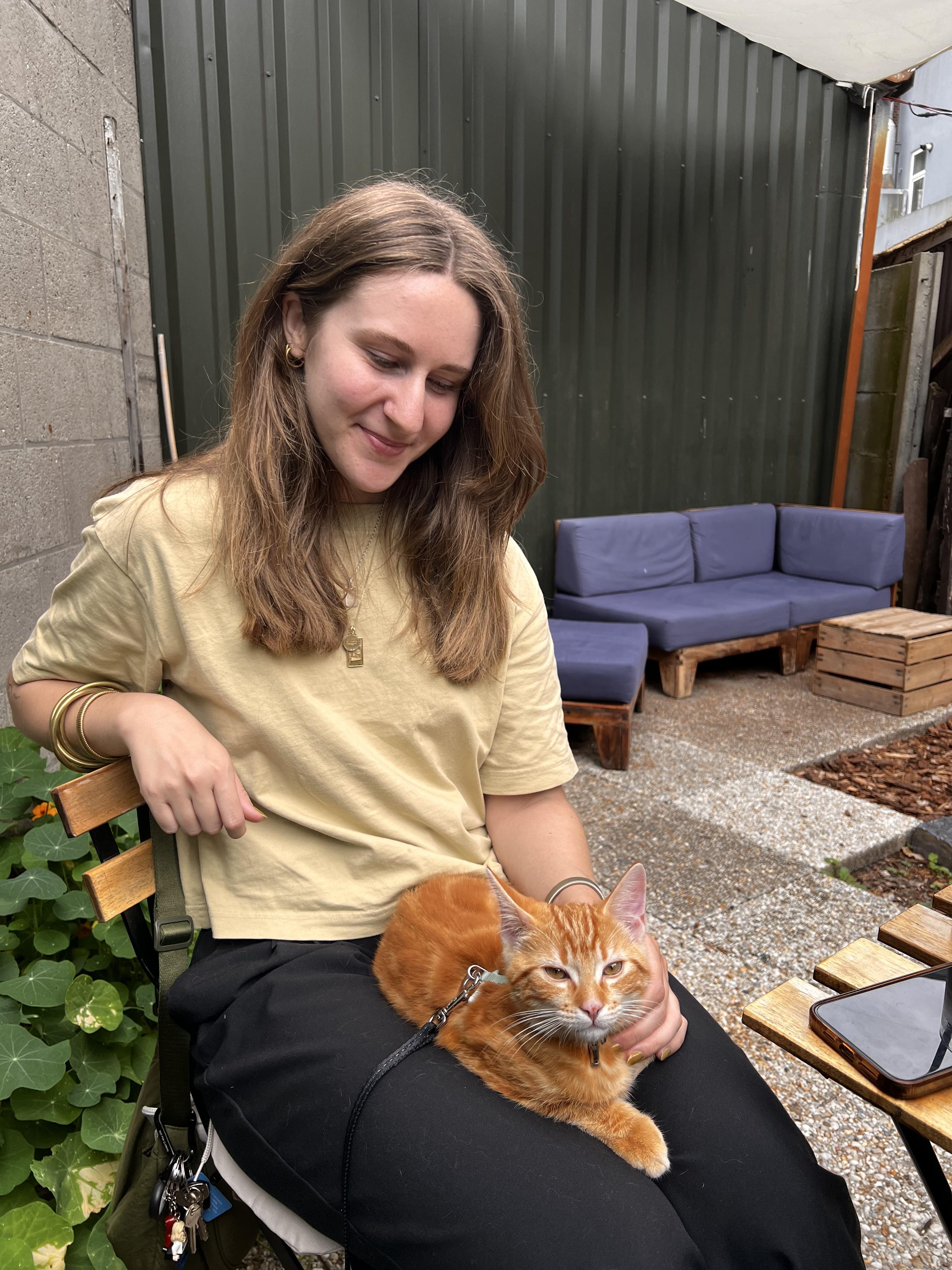Midori Fuchs smiling while holding a ginger cat outdoors